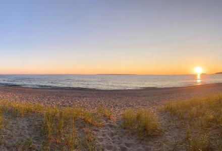 A wide angle photo of the sun on a Great Lake.